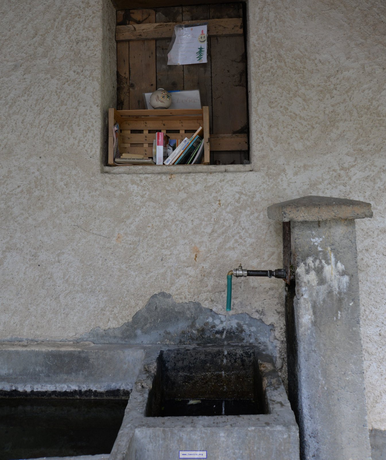 Dans une niche en hauteur au-dessus du bac de la fontaine.
