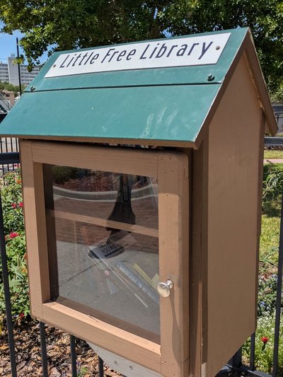 This Little Free Library is located on the Sebring Circle adjacent to the Circle Theater. It faces the circle and is easy to access on foot. Painted brown with a green roof, it has a single door with a clear panel. Inside, two shelves where all kinds of books can be found.